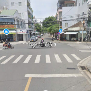 Intersection on Ngô Gia Tự street with zebra crosswalks, buildings, and motorbikes waiting at the curb.