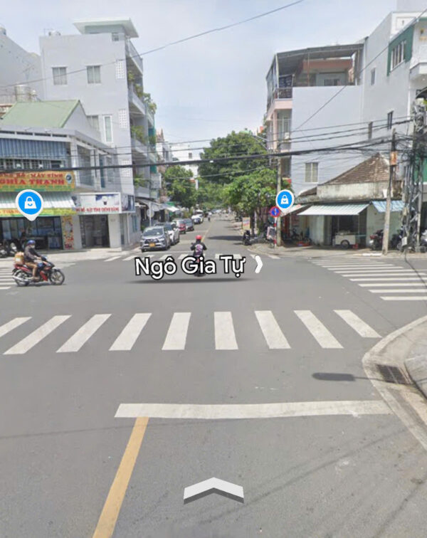 Intersection on Ngô Gia Tự street with zebra crosswalks, buildings, and motorbikes waiting at the curb.